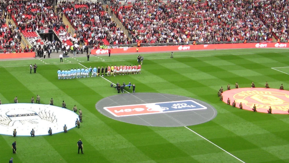 Jogadores de Manchester City e Manchester United perfilados no gramado de Wembley antes de uma partida