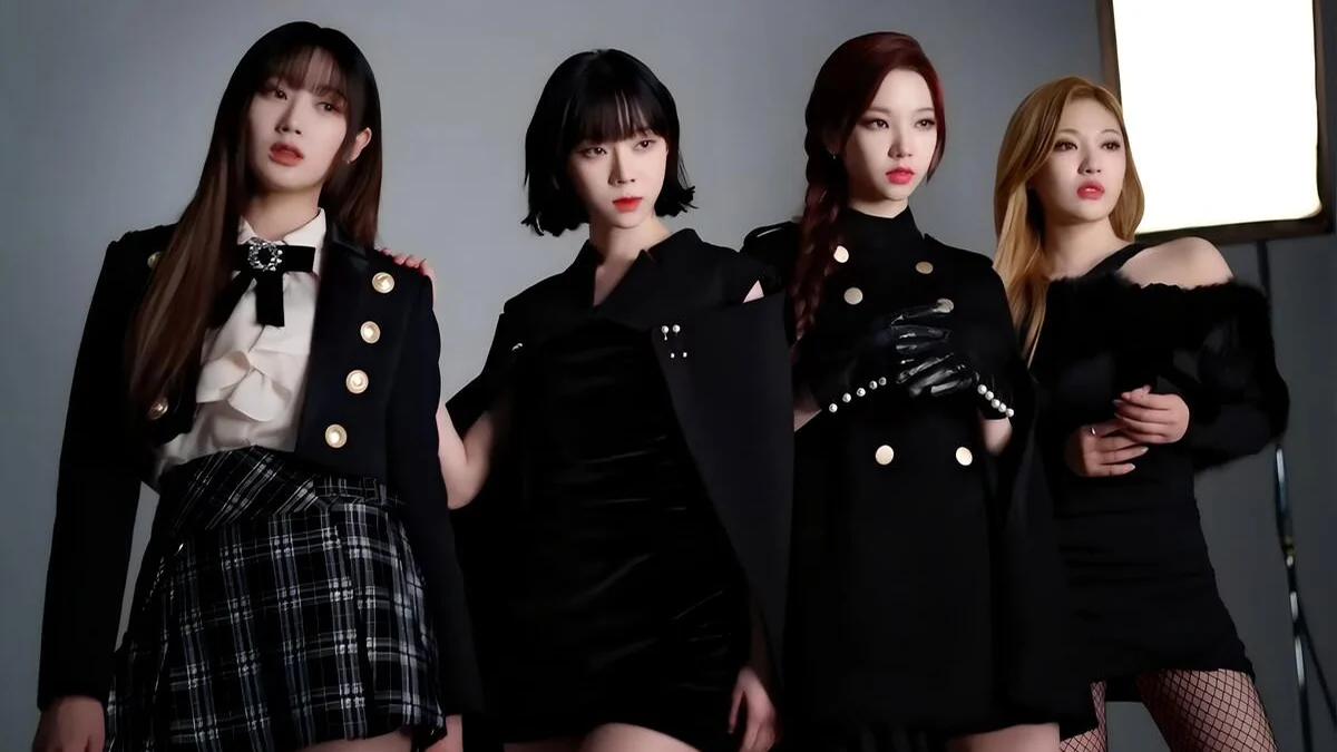 The four aespa members pose in black outfits in a studio, with a light panel at right.