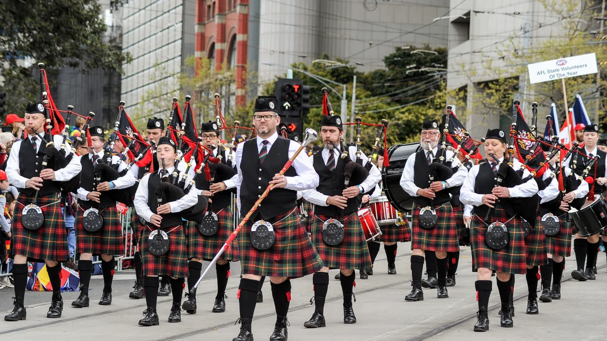 Banda de gaitas con uniformes de tartán marchando por una calle de Melbourne