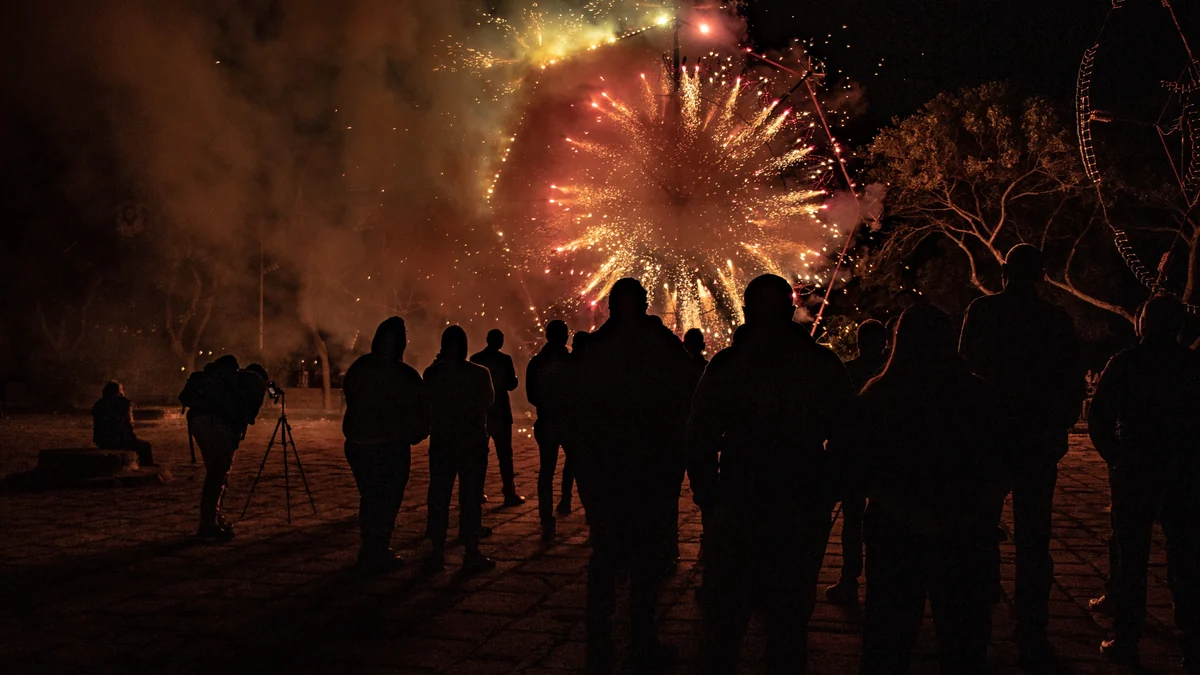 Un public regarde une roue de feux d’artifice pendant une célébration nocturne en plein air