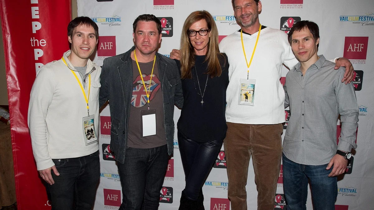 Allison Janney, con gafas, posa en el centro de un grupo de cinco personas ante un panel de festival.