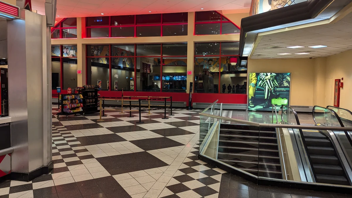 Interior do AMC Kips Bay com piso quadriculado, área de filas e escadas rolantes