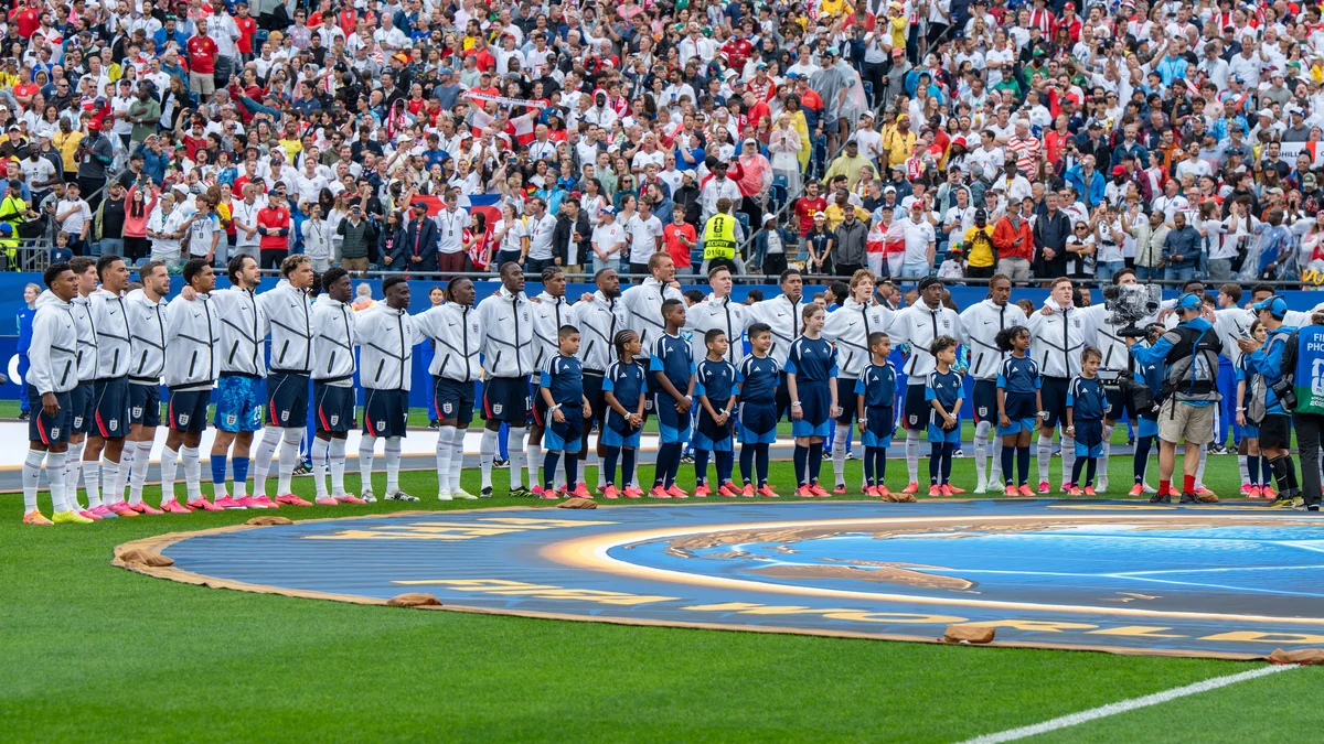 England players line up with children on the pitch in front of the crowd.