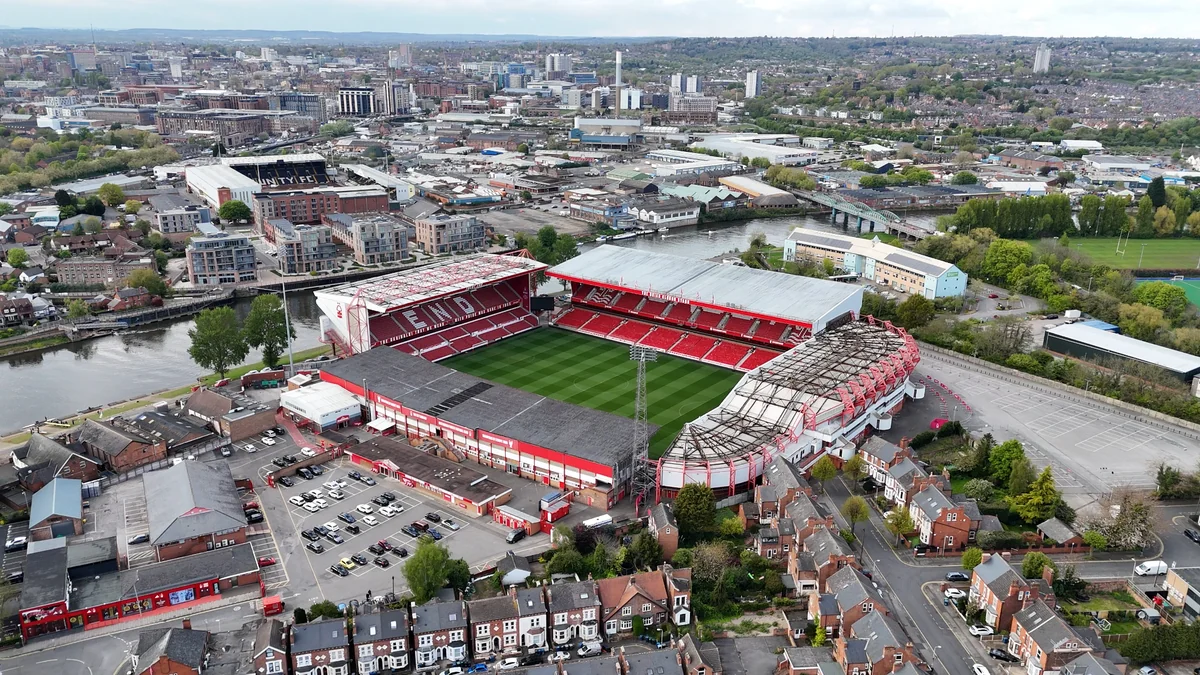 Vue aérienne du City Ground, avec ses tribunes rouges au bord de la Trent et Nottingham à l’arrière-plan.