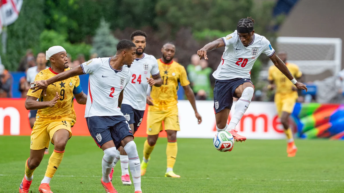 Noni Madueke, en blanc, contrôle le ballon dans les airs pendant Angleterre-Ghana, entouré d’autres joueurs.
