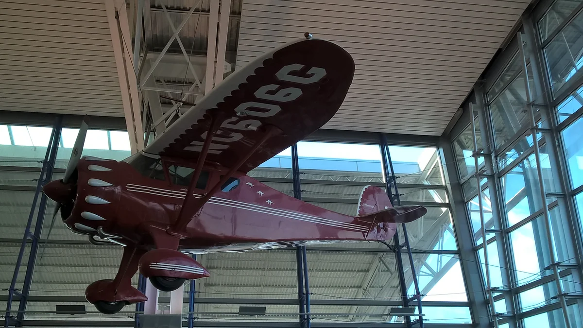 Historic red airplane suspended inside a glass-walled airport terminal