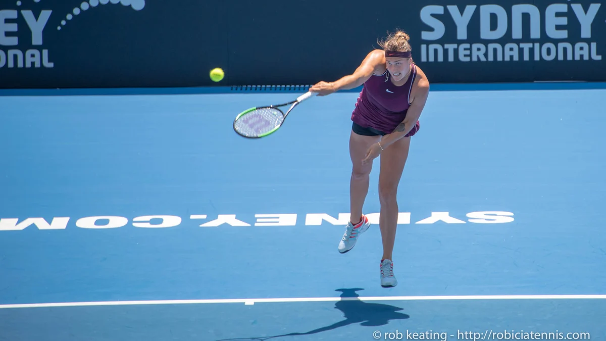 Aryna Sabalenka golpea la pelota durante un saque en una pista azul.