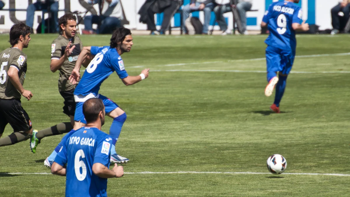 Getafe CF players in blue run toward the ball during a match