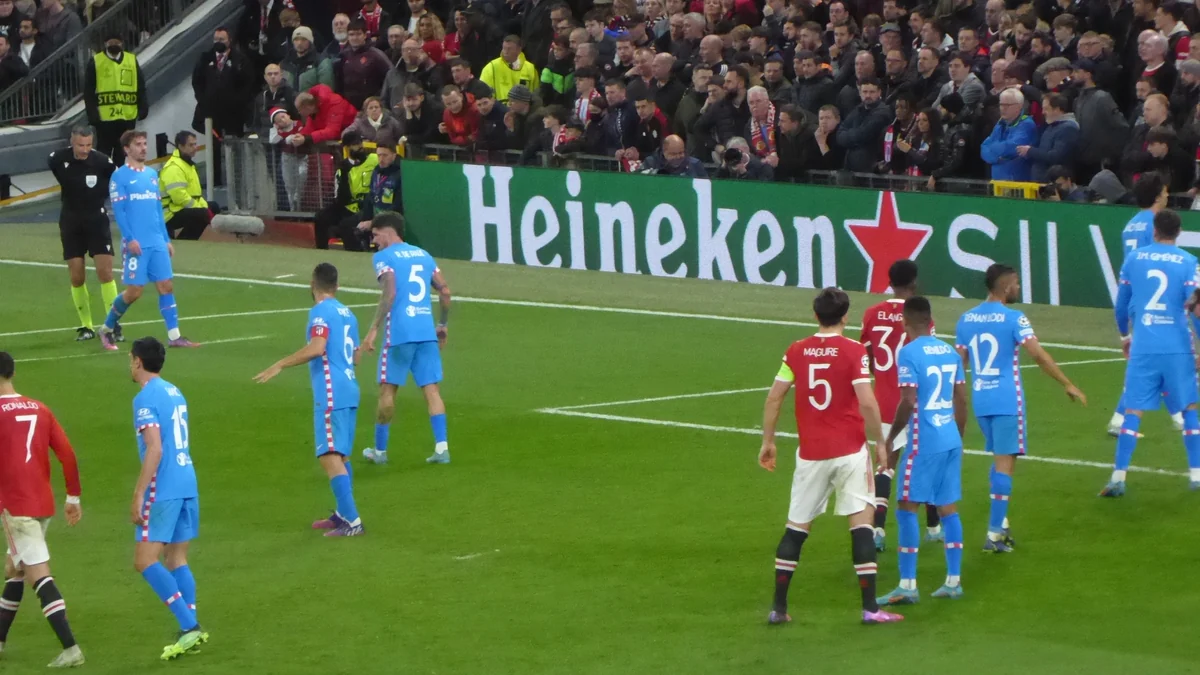 Jogadores do Atlético de Madrid, de azul, e do Manchester United, de vermelho, aguardam uma cobrança perto da área