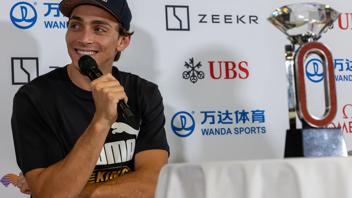 Mondo Duplantis sonrí mientras sostiene un micrófono, con un trofeo a la derecha