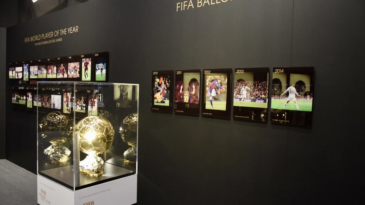 Troféu dourado em uma vitrine diante de painéis com vencedores de prêmios de futebol