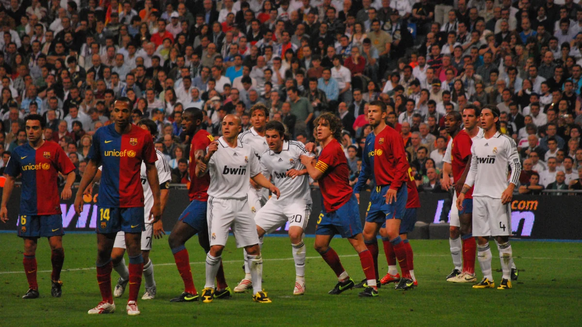 Des joueurs de Barcelone et du Real Madrid se regroupent dans la surface pendant un match.