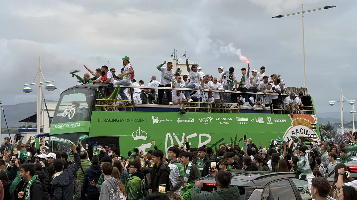 Racing players and supporters celebrate around a green open-top bus