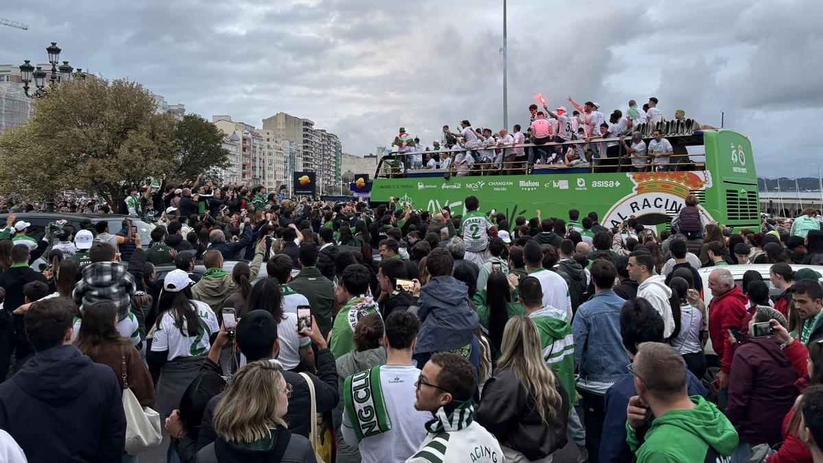 A crowd in green shirts and scarves surrounds the Racing bus by the waterfront