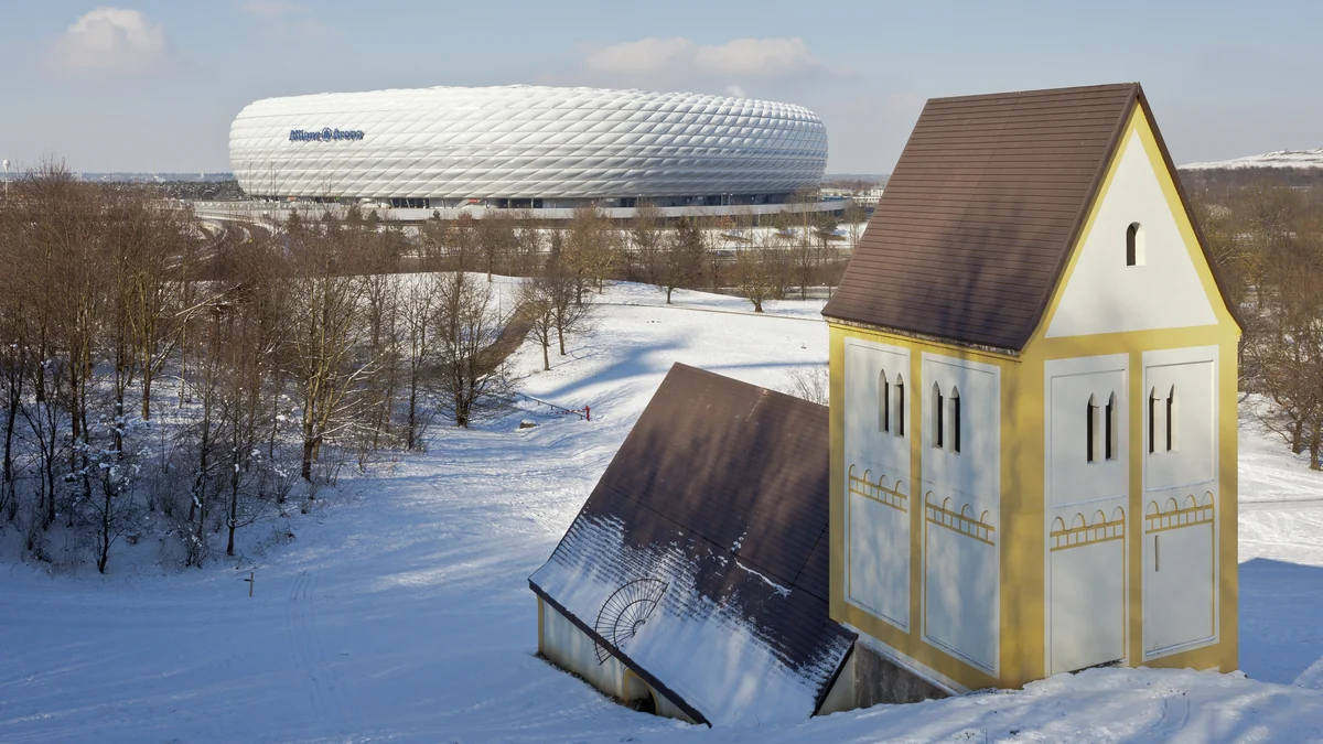 Church replica in a snowy landscape with the Allianz Arena in the background
