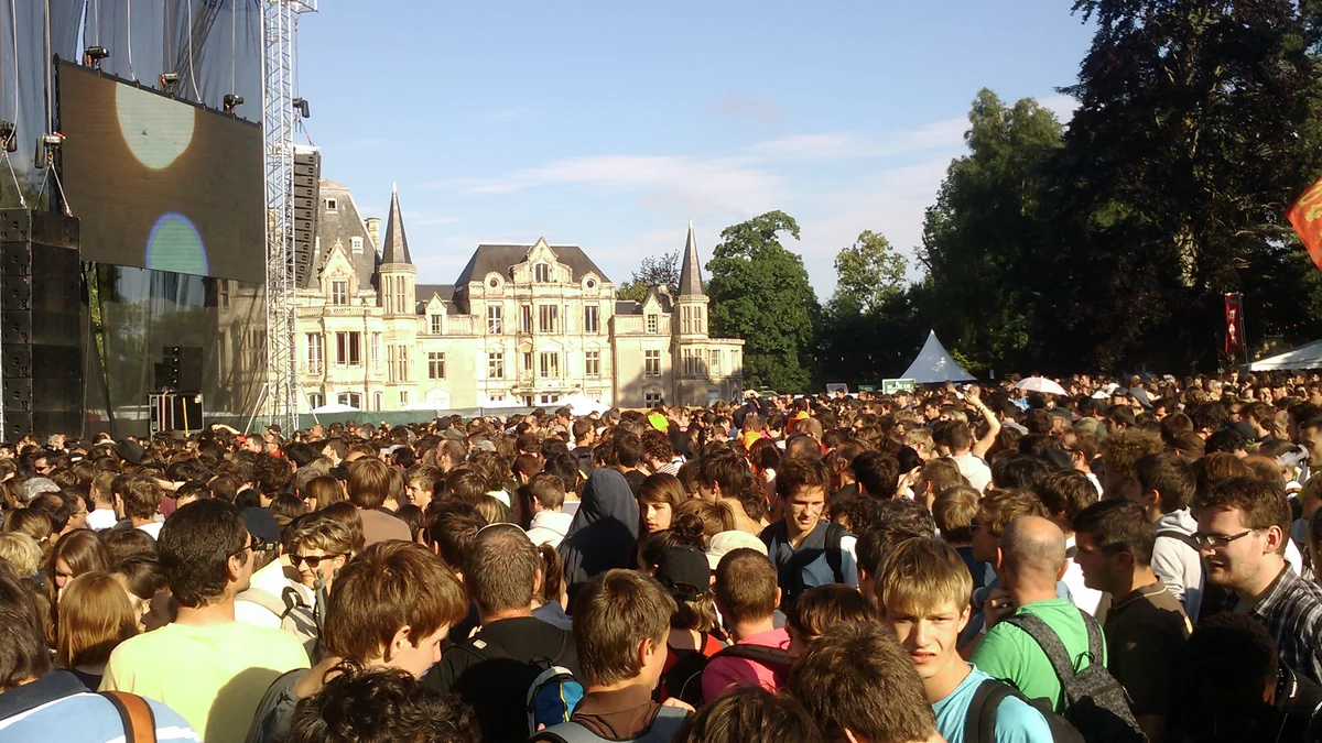 Crowd in front of a stage beside the Château de Beauregard on a sunny day