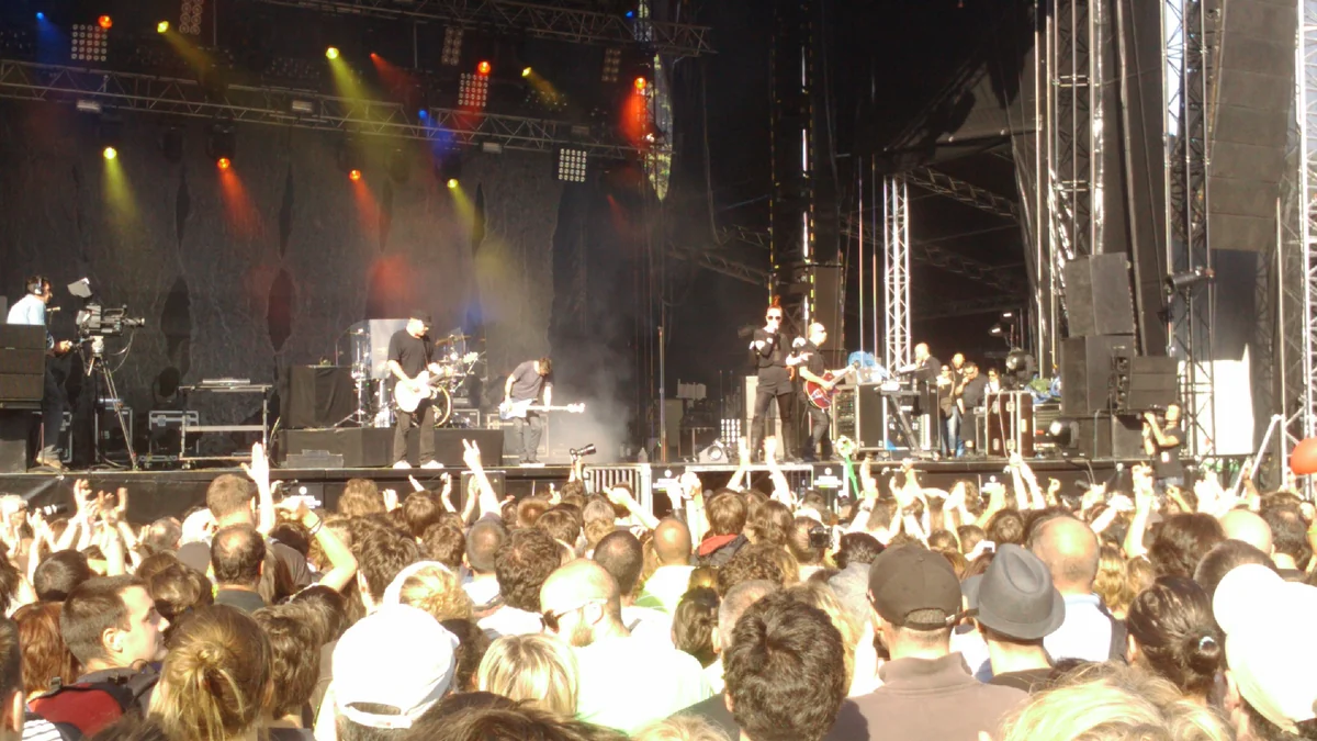 Band on a large stage before a sunlit crowd