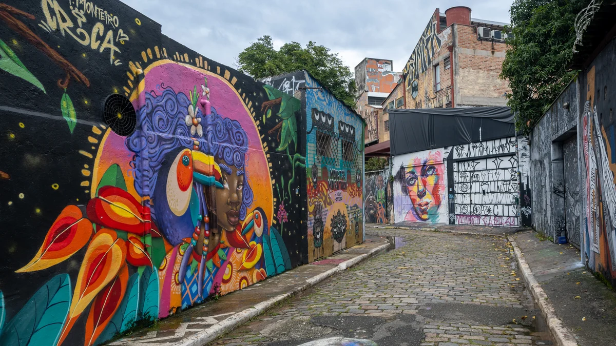 Passage pavé bordé de grandes fresques colorées au Beco do Batman