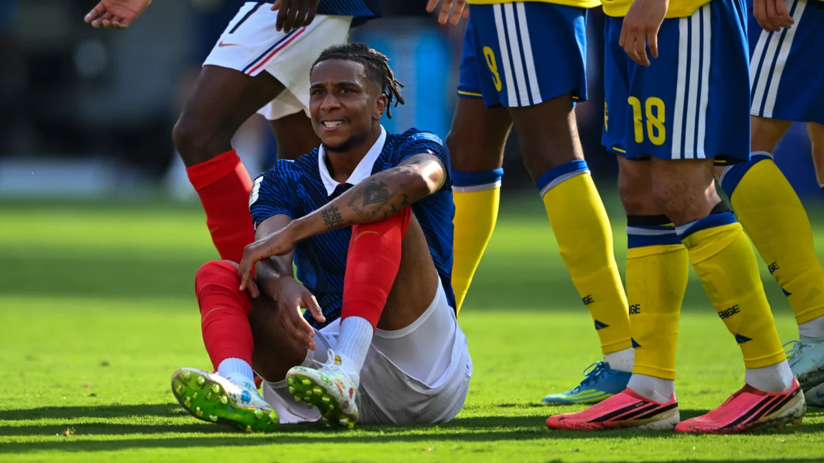 Michael Olise sentado no gramado com jogadores da Suécia ao redor