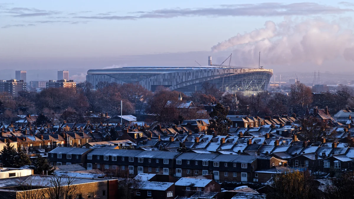 Tottenham Hotspur Stadium seen in the distance behind houses with snow-covered roofs