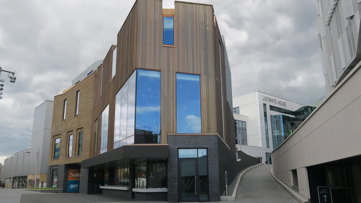 Brown-clad Paxton building with large windows beside Tottenham Hotspur Stadium