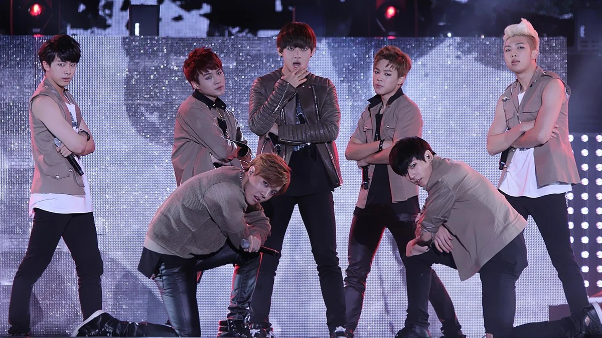 Seven BTS members pose onstage during a performance
