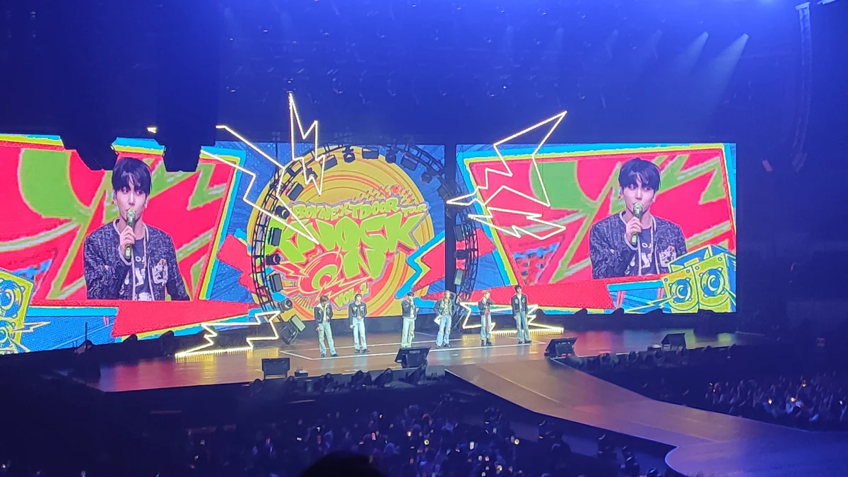 BOYNEXTDOOR lined up onstage in front of large colorful screens