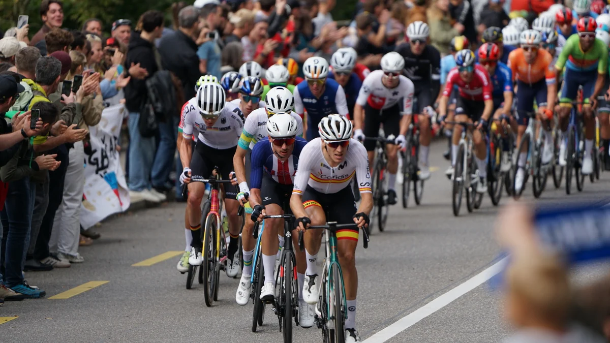 Brandon McNulty rides near the front of the peloton on a climb, with other cyclists and spectators around him