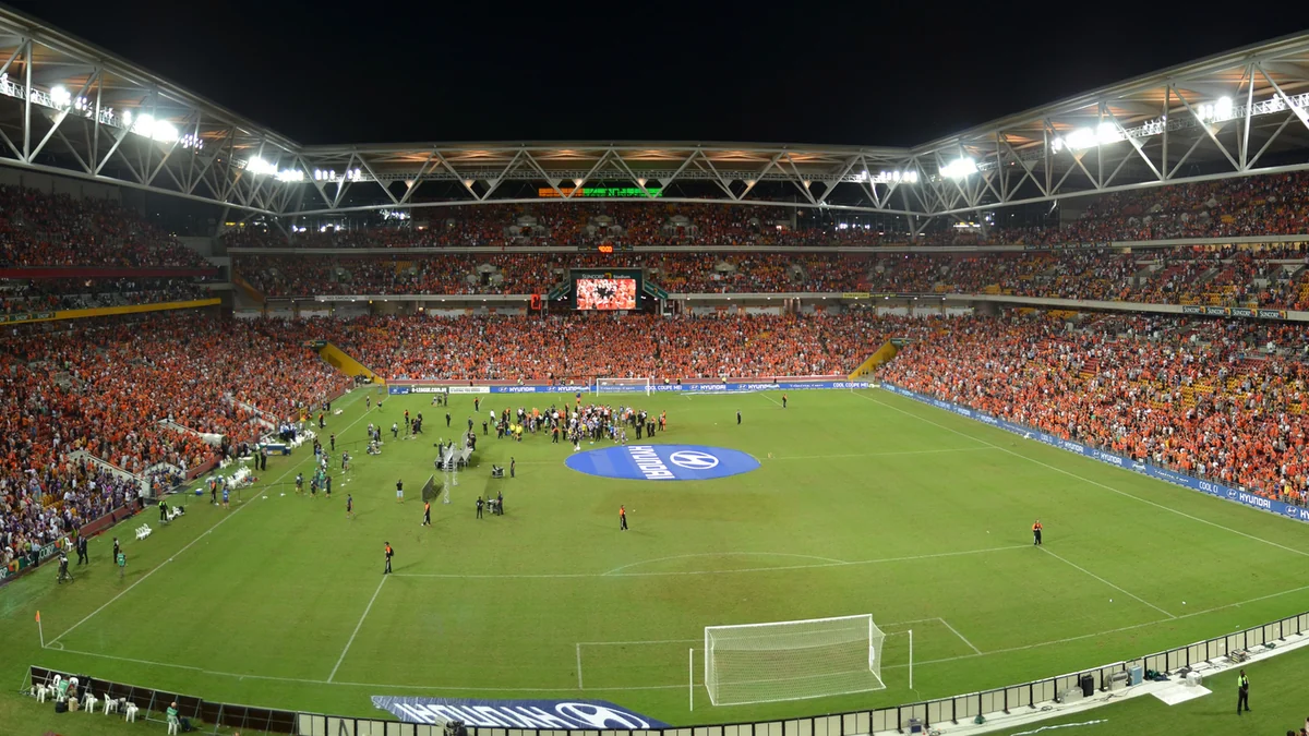 Campo de futebol e arquibancadas lotadas sob refletores no Suncorp Stadium