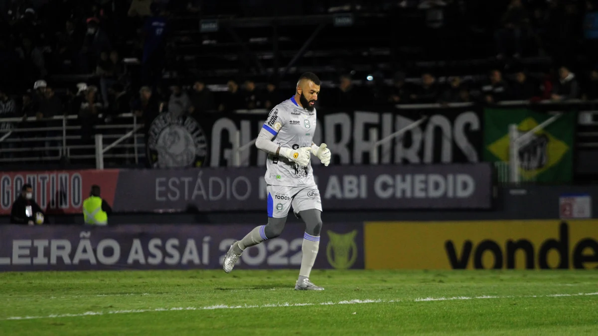 Goleiro de uniforme cinza corre pelo campo durante partida noturna