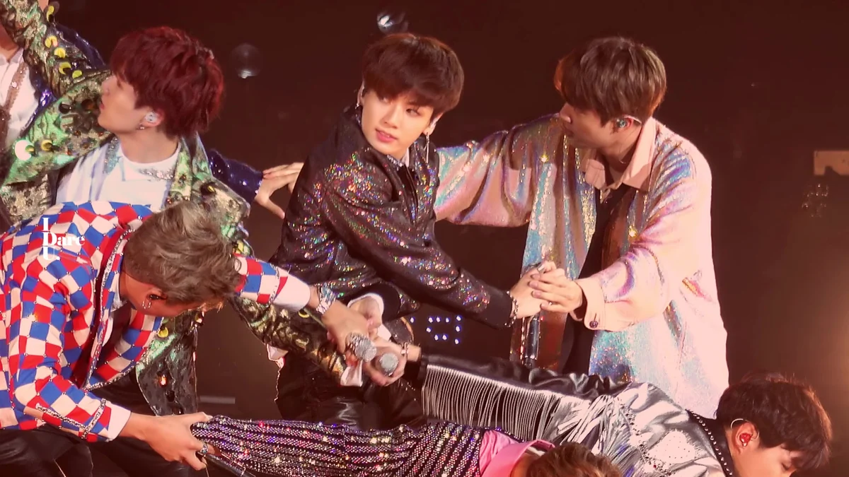 Integrantes de BTS reunidos durante una actuación con vestuario colorido y brillante