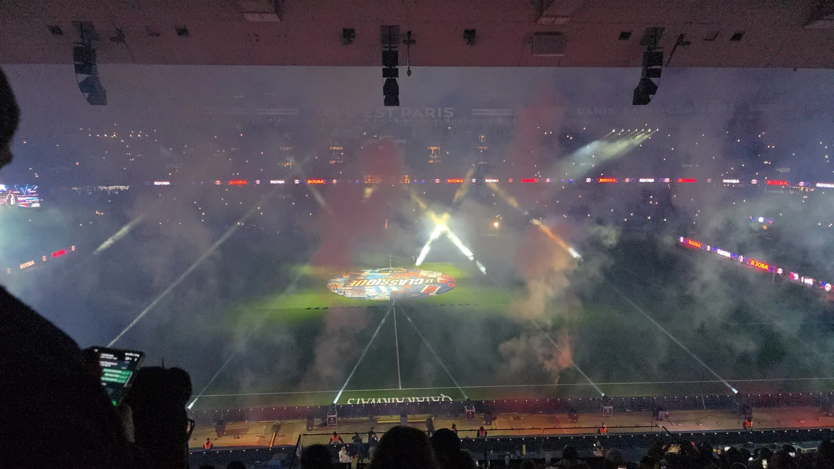Football pitch viewed from the stands through smoke and beams of light before a match.