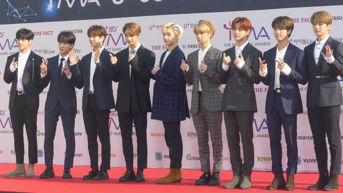 Nueve integrantes de Stray Kids posan con traje en una alfombra roja