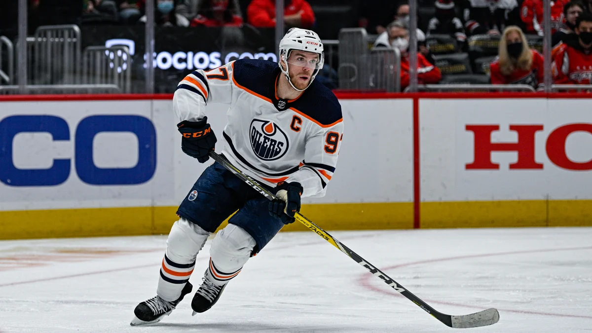 Connor McDavid skates with the puck in a white Edmonton Oilers uniform
