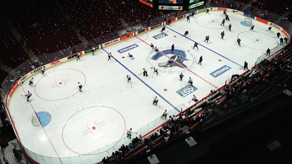 Overhead view of Canucks and Oilers players warming up in a hockey arena
