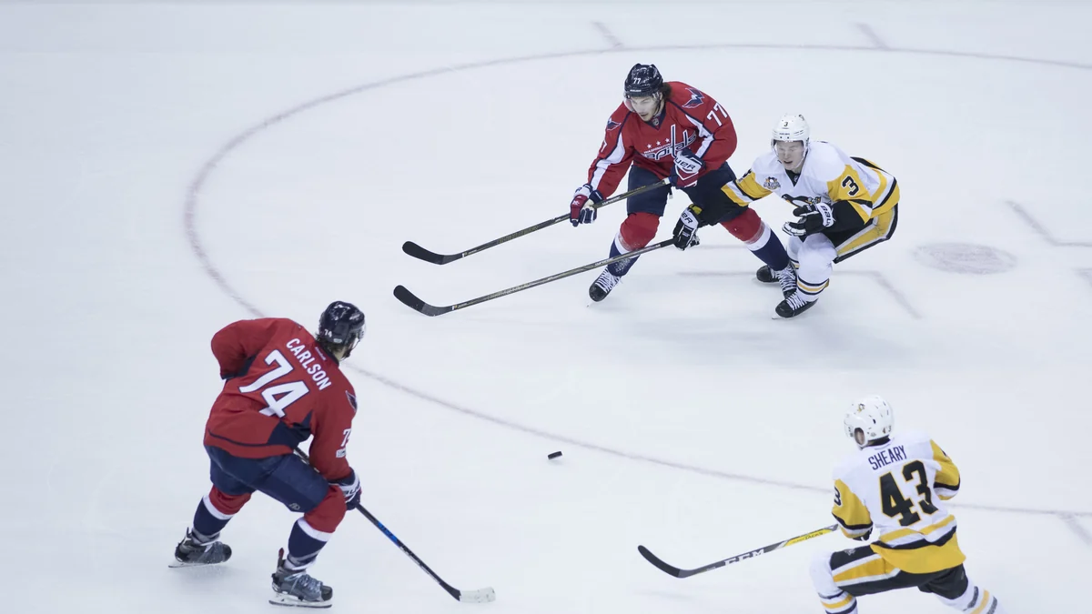 Des joueurs des Capitals avancent avec le palet tandis que les Penguins se replient en défense