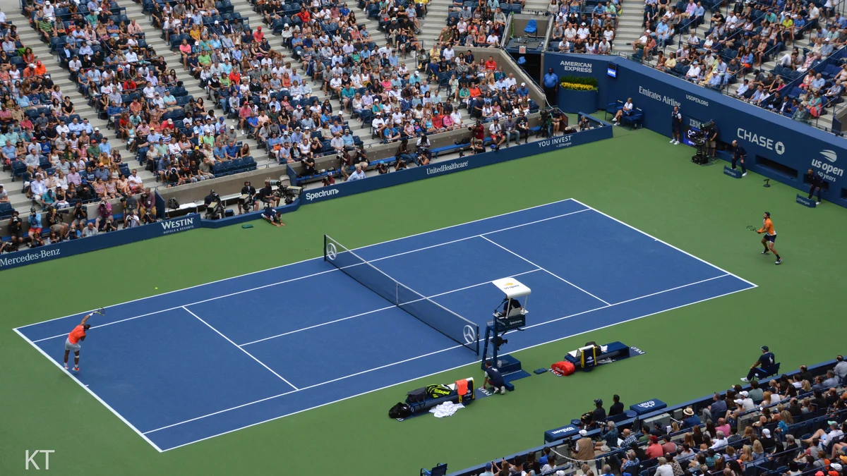Wide view of a blue tennis court, with Rafael Nadal on the left and Karen Khachanov on the right before crowded stands.