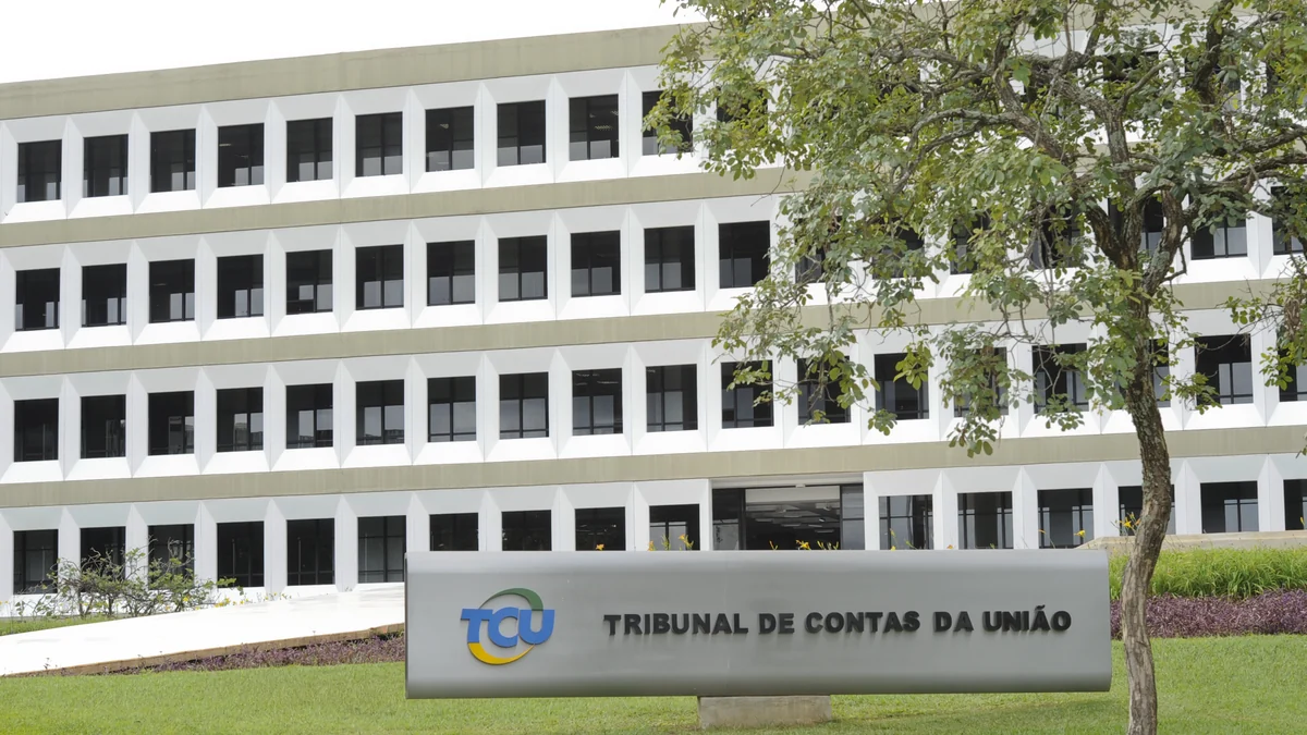 Placa do Tribunal de Contas da União diante da fachada e de uma árvore