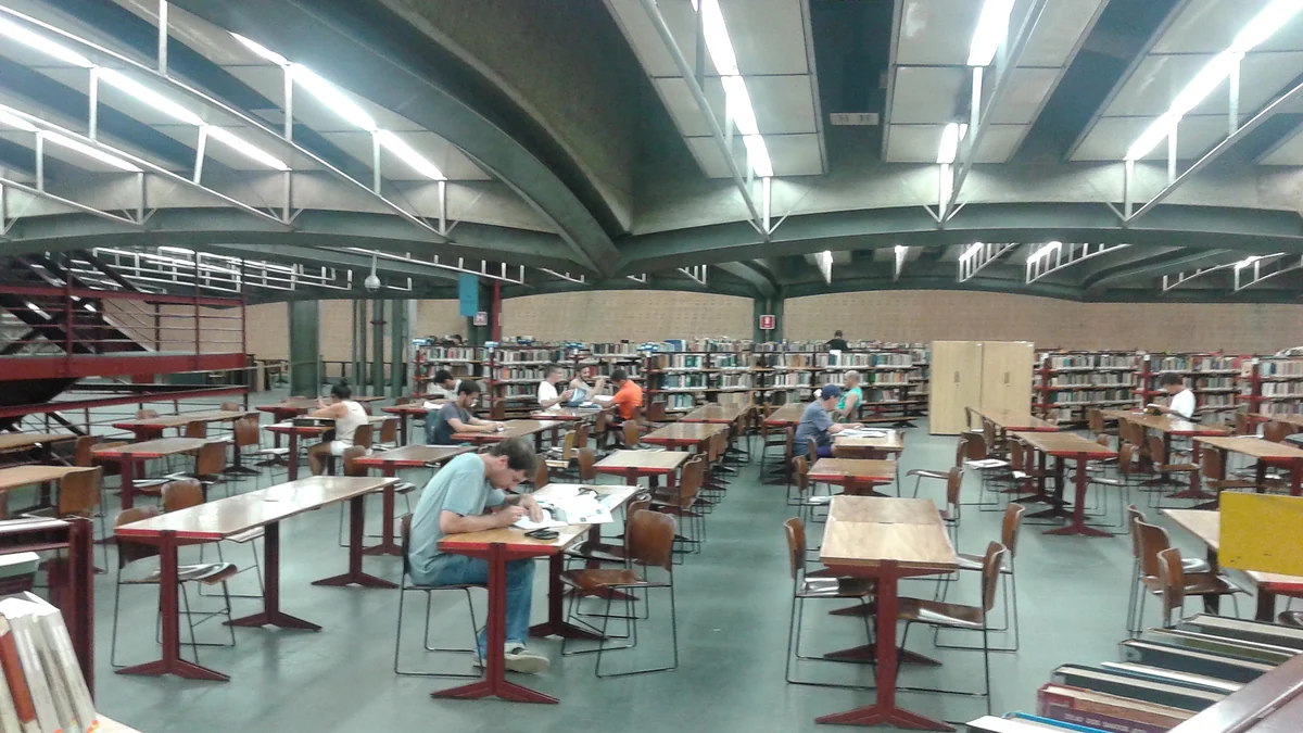 Sala da Biblioteca Sérgio Milliet com mesas, cadeiras, estantes e pessoas estudando