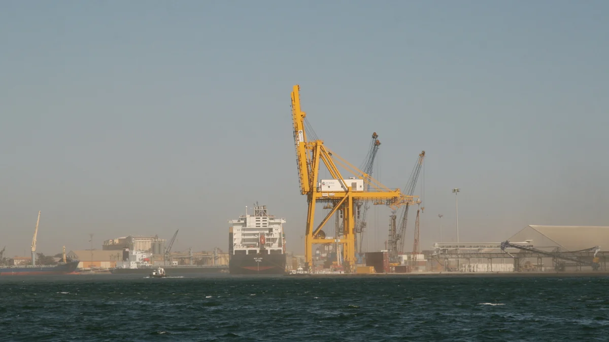 Cargo ship and large yellow cranes at the Port of Dakar, viewed from the water