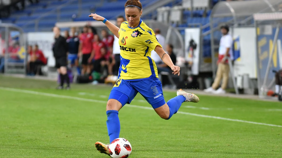 Player in a yellow and blue kit strikes the ball near the touchline