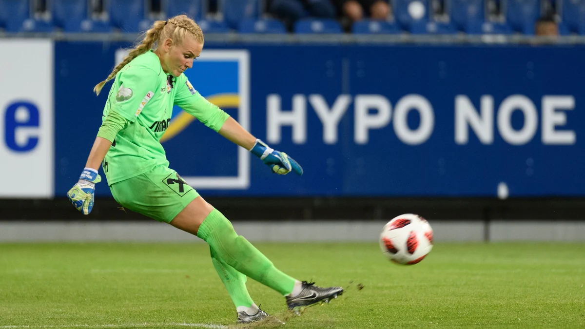 Goalkeeper in a green kit kicks the ball on the pitch during a match
