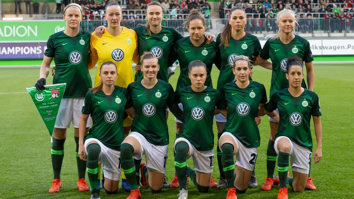 Wolfsburg players pose in two rows on the pitch before a match