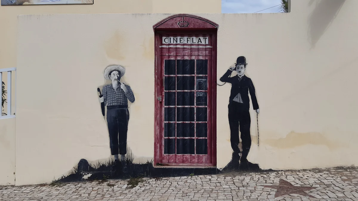 Fresque représentant Charlie Chaplin avec chapeau melon et canne, près d’une porte rouge peinte