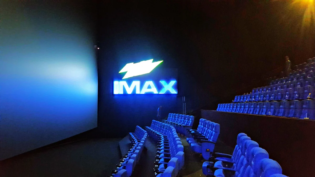 Empty cinema auditorium with blue seats, screen and IMAX sign
