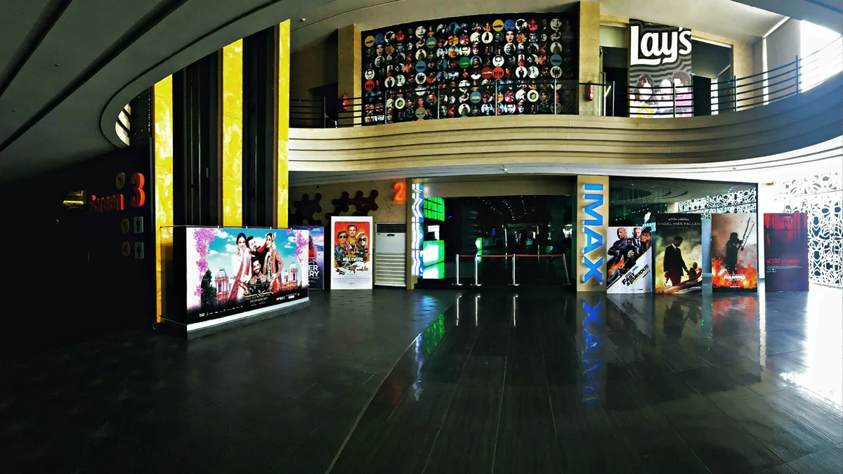 Wide cinema lobby with numbered auditorium entrances, posters and an IMAX sign