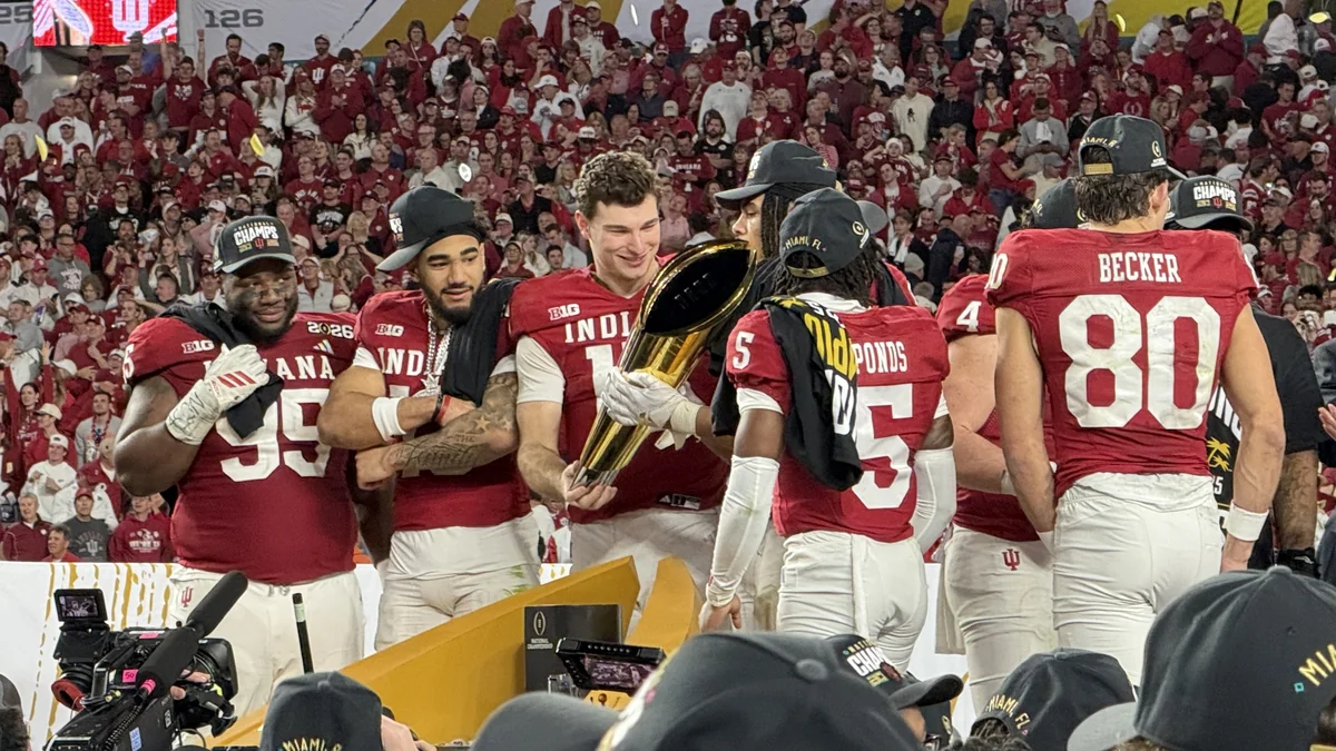 Jogadores de Indiana reunidos em torno do troféu do College Football Playoff no gramado
