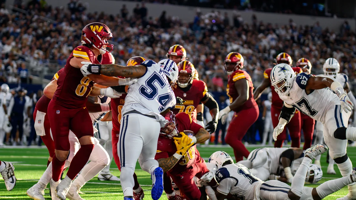 Jugadores de Washington Commanders y Dallas Cowboys disputan una jugada en el centro del campo.