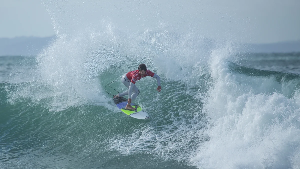 Surfista con licra roja completa una maniobra ante la espuma de una ola