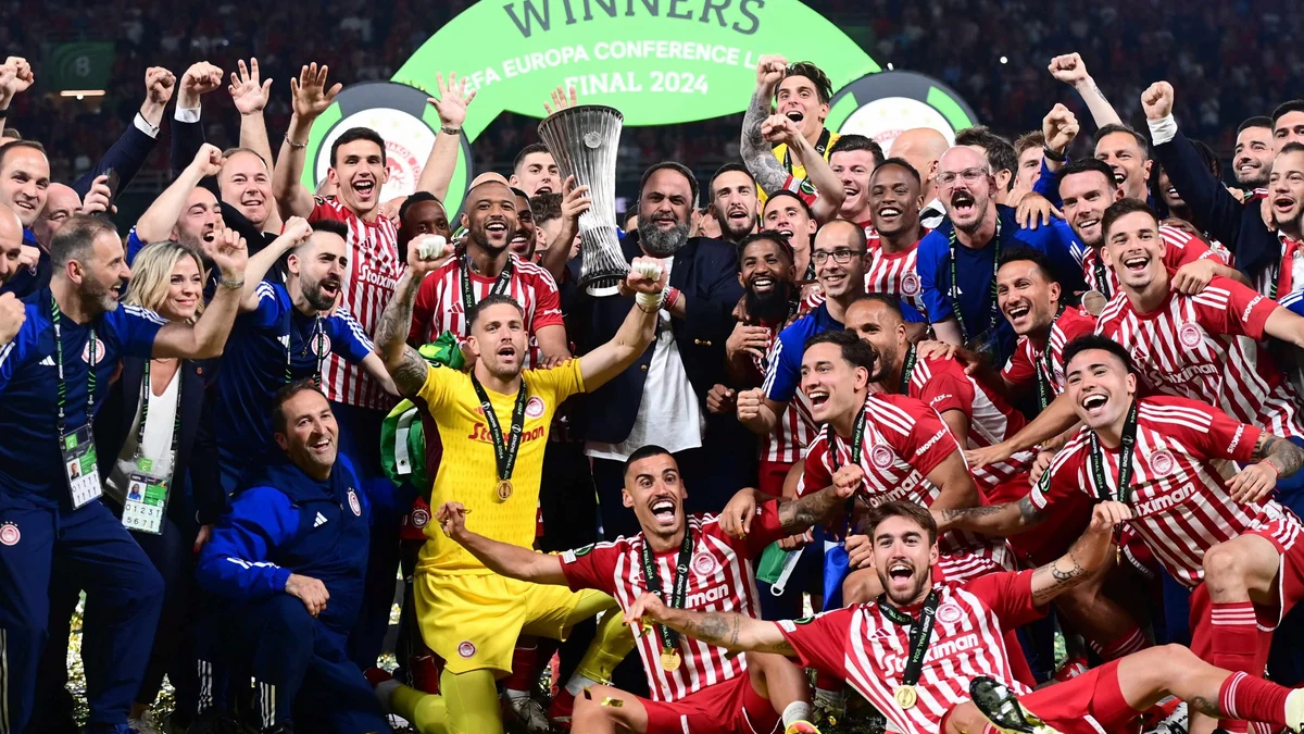 Jogadores e integrantes de uma equipe comemoram ao redor da taça da Conference League